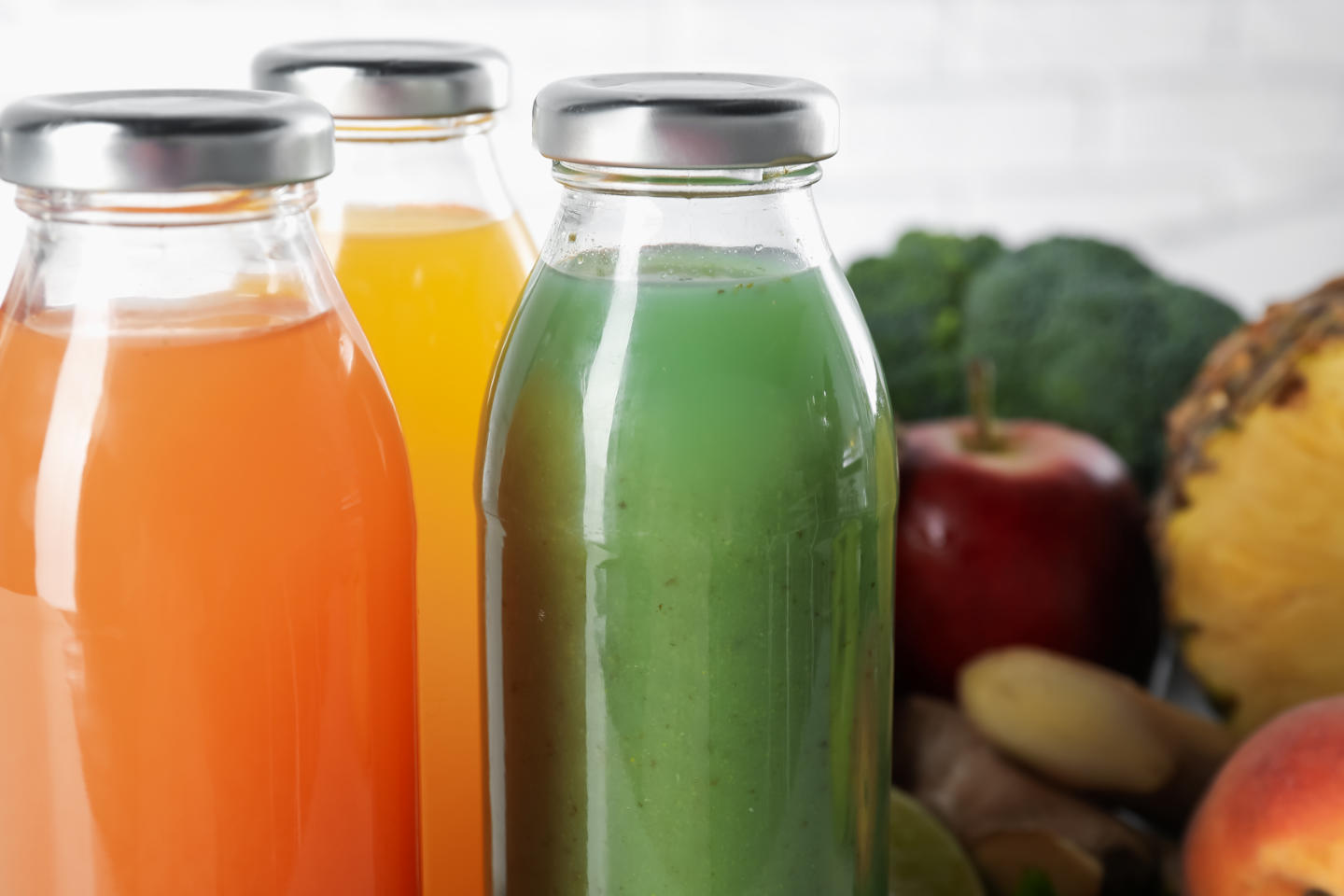 Tasty juices in glass bottles and ingredients on blurred backgro